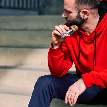 tired sportsman sitting on stairs outdoors and eating energy bar