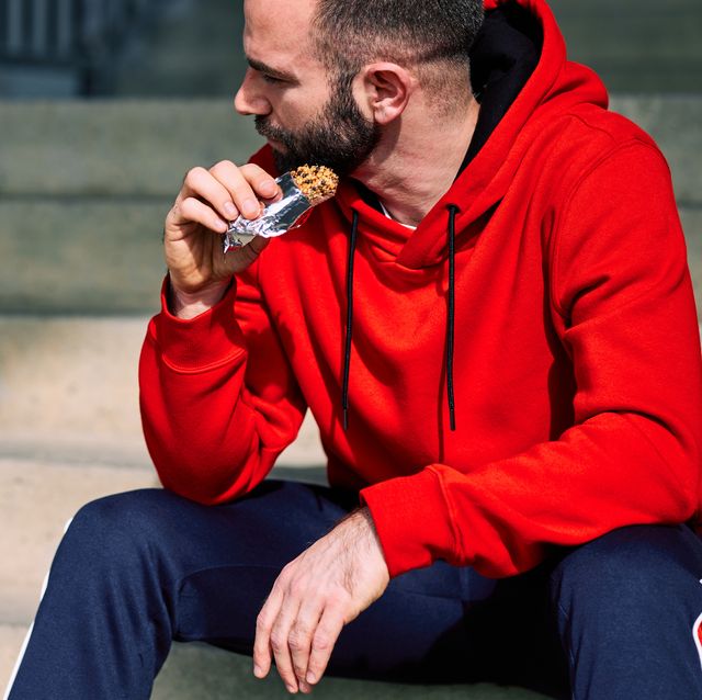 tired sportsman sitting on stairs outdoors and eating energy bar