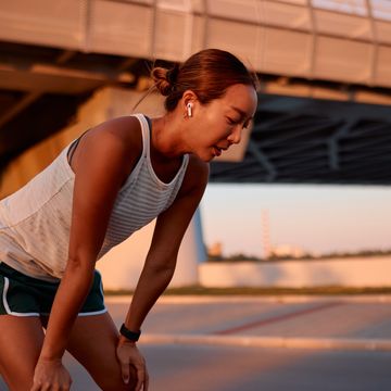 tired sportswoman resting after running workout under bridge