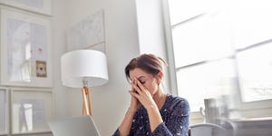 Tired, stressed businesswoman at laptop with head in hands