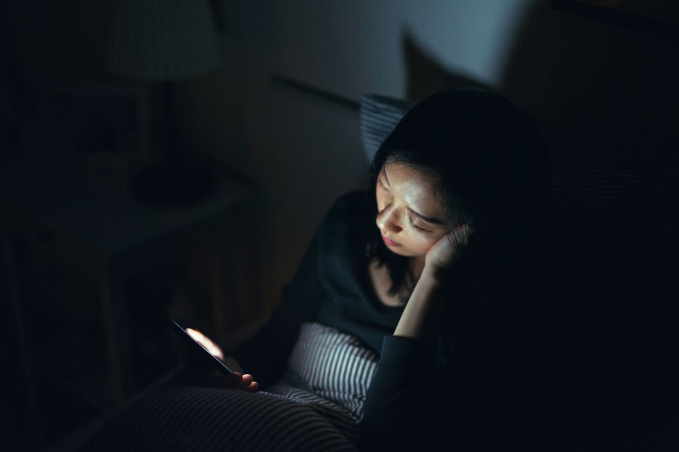 tired woman fell asleep while using smartphone in bed at night