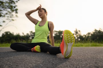 tired woman runner taking a rest after running hard in the park sweating fitness woman tired exausted of running in sun heat dehydrated with sweat dripping from face athlete jogger jogging outside in city