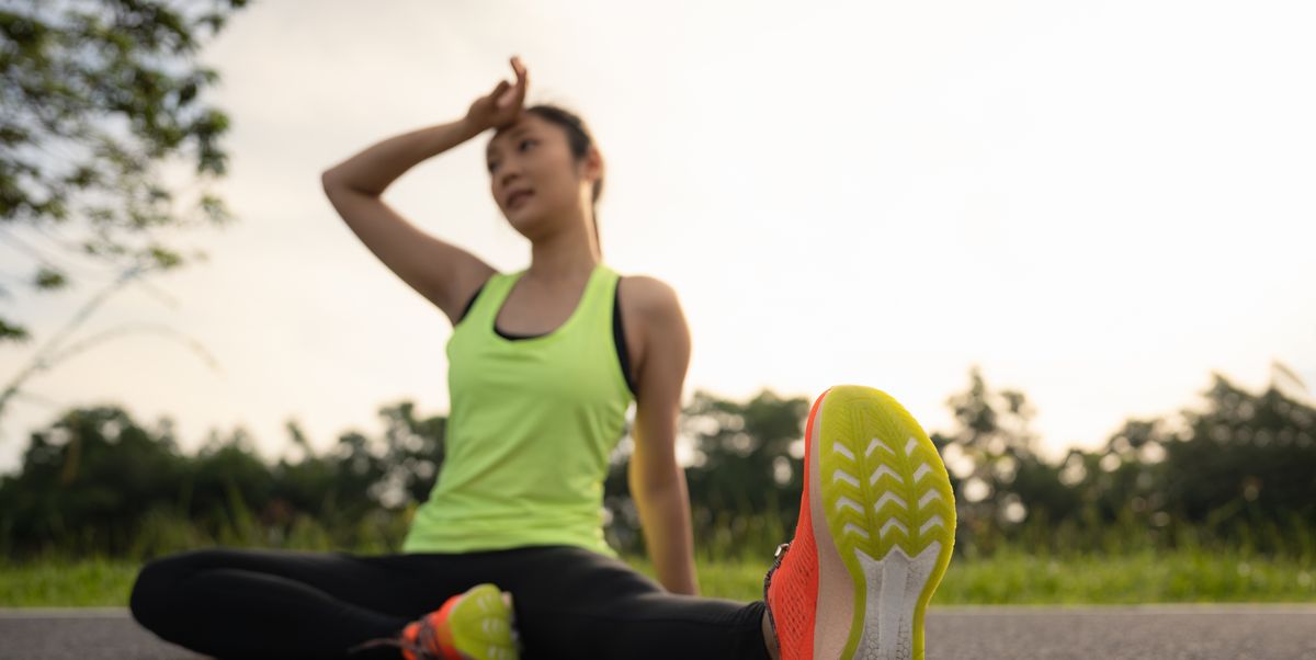 tired woman runner taking a rest after running hard in the park. sweating fitness woman tired exausted of running in sun heat dehydrated with sweat dripping from face. athlete jogger jogging outside in city.