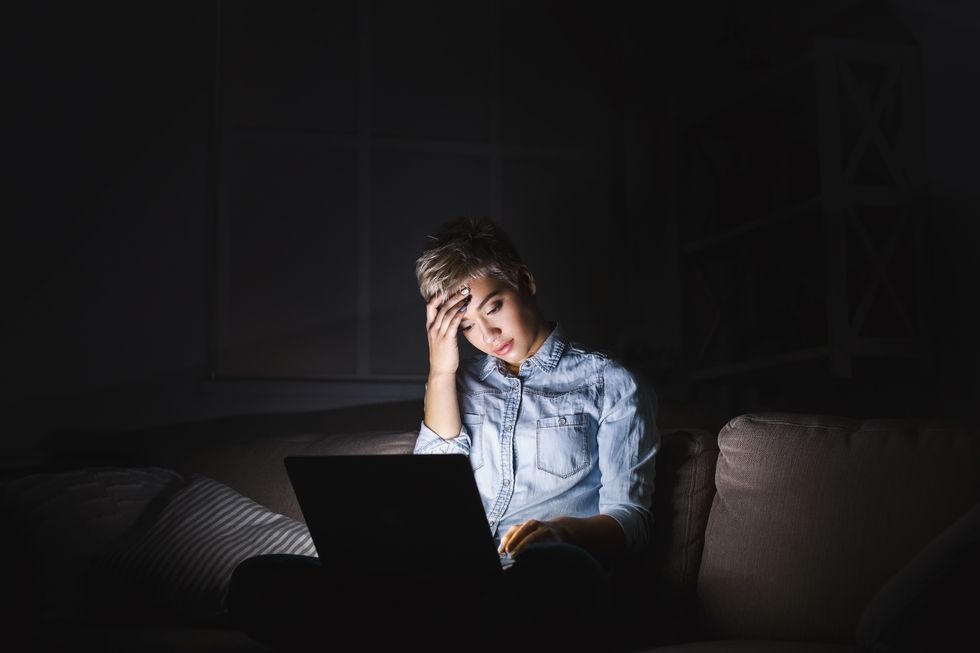 tired woman with laptop at dark home office copy space