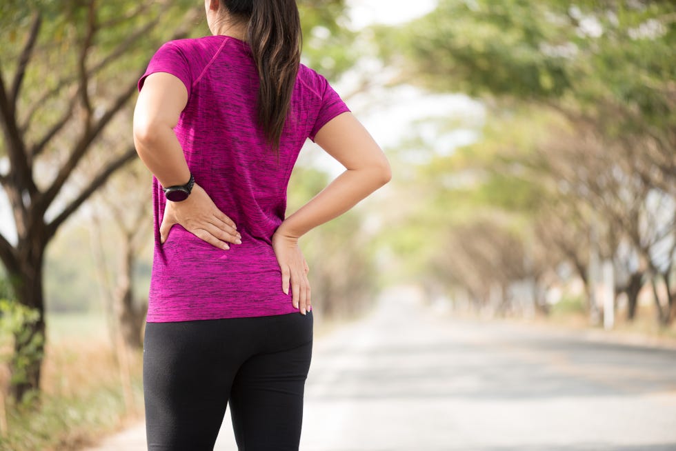 tired young asian sport girl feel pain on her back and hip while exercising, health care concept