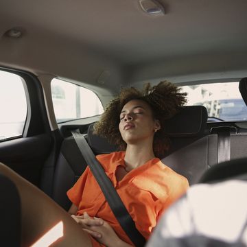 Tired young woman sleeping in back seat of car