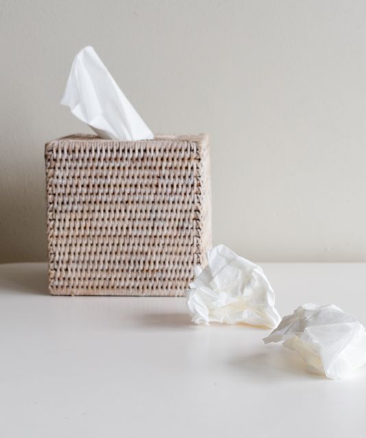 Tissue box and crumpled tissues on white table