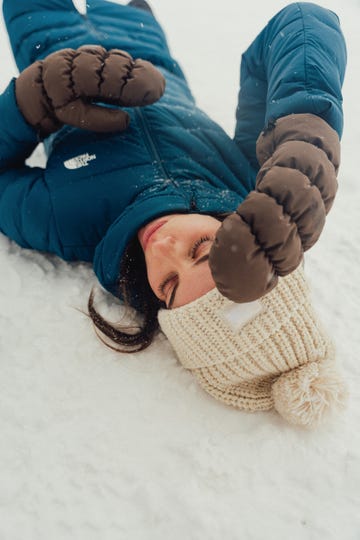 person lying in snow wearing winter clothing