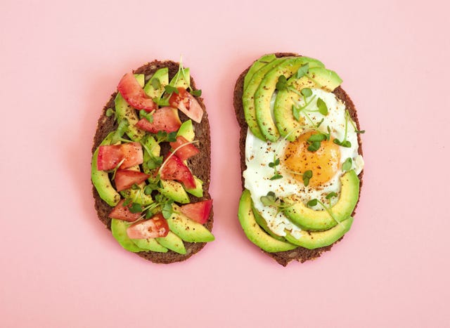 toasts of dark bread with avocado slices, red tomatoes, fried egg and microgreen