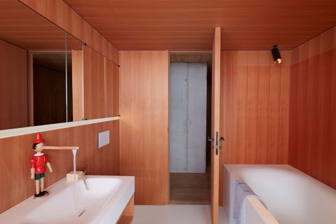 a wood bathroom with sink, tub, and faucet shaped like a pinocchio toy