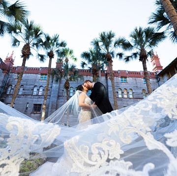 a man and woman kissing on a white tarp in front of a building with palm trees