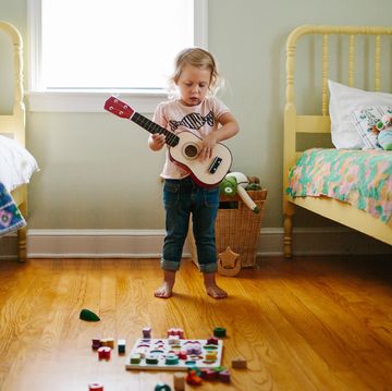 toddler playing guitar in bedroom with two yellow beds
