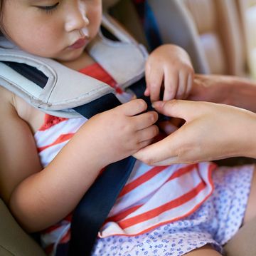mom buckling toddler into car seat