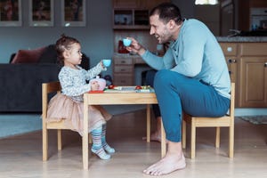 toddler girl and dad toast while having tea party