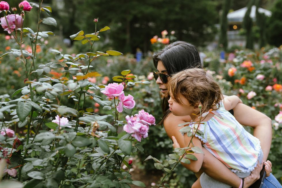 toddler girl smelling flowers while at the park