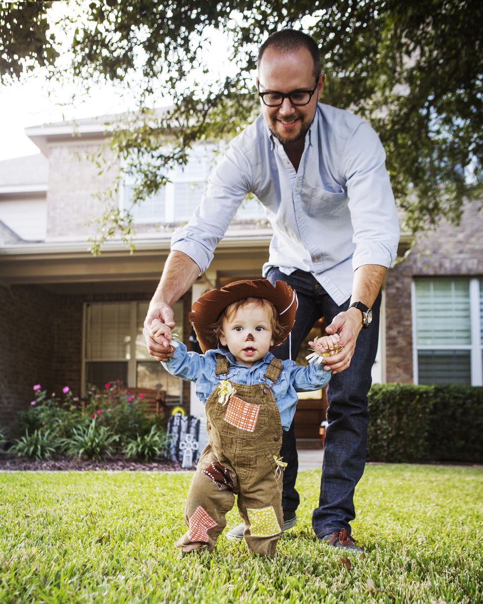 father holding baby boy dressed as cowboy at backyard