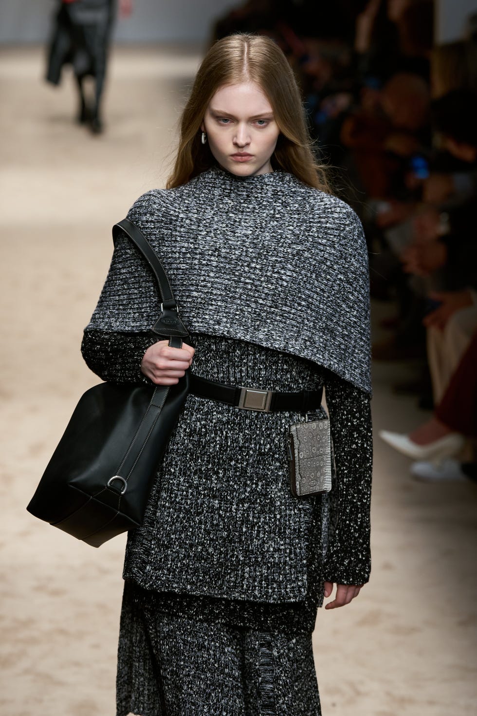 Fashion model showcasing a textured outfit with accessories on the runway