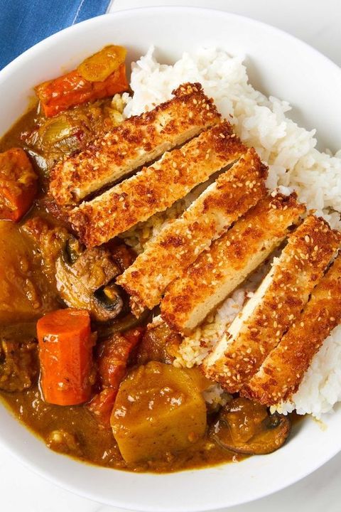 white rice, sesame panko crusted tofu, tender vegetables, and a rich and flavorful curry sauce in a white bowl