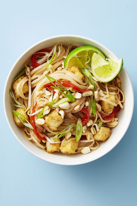 a bowl of tofu pad thai with a lime wedge