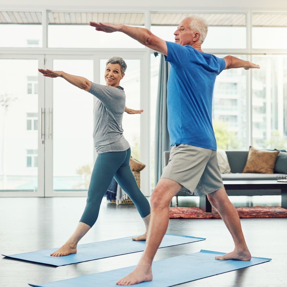 older white couple in warrior 2 yoga pose indoors