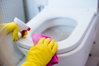 toilet bowl cleaning woman in yellow rubber gloves cleaning toilet with pink cloth