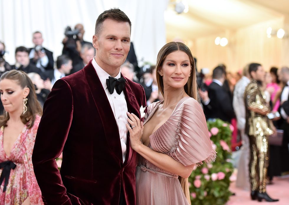 tom brady and gisele bundchen leaning in towards each other and posing for a photo