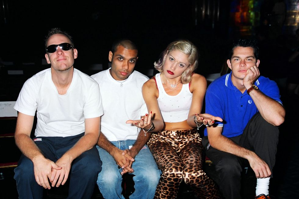no doubt members tom dumont, tony kanal, gwen stefani, and adrian young sit in a row and look at the camera, stefani holds her hands up in a what motion