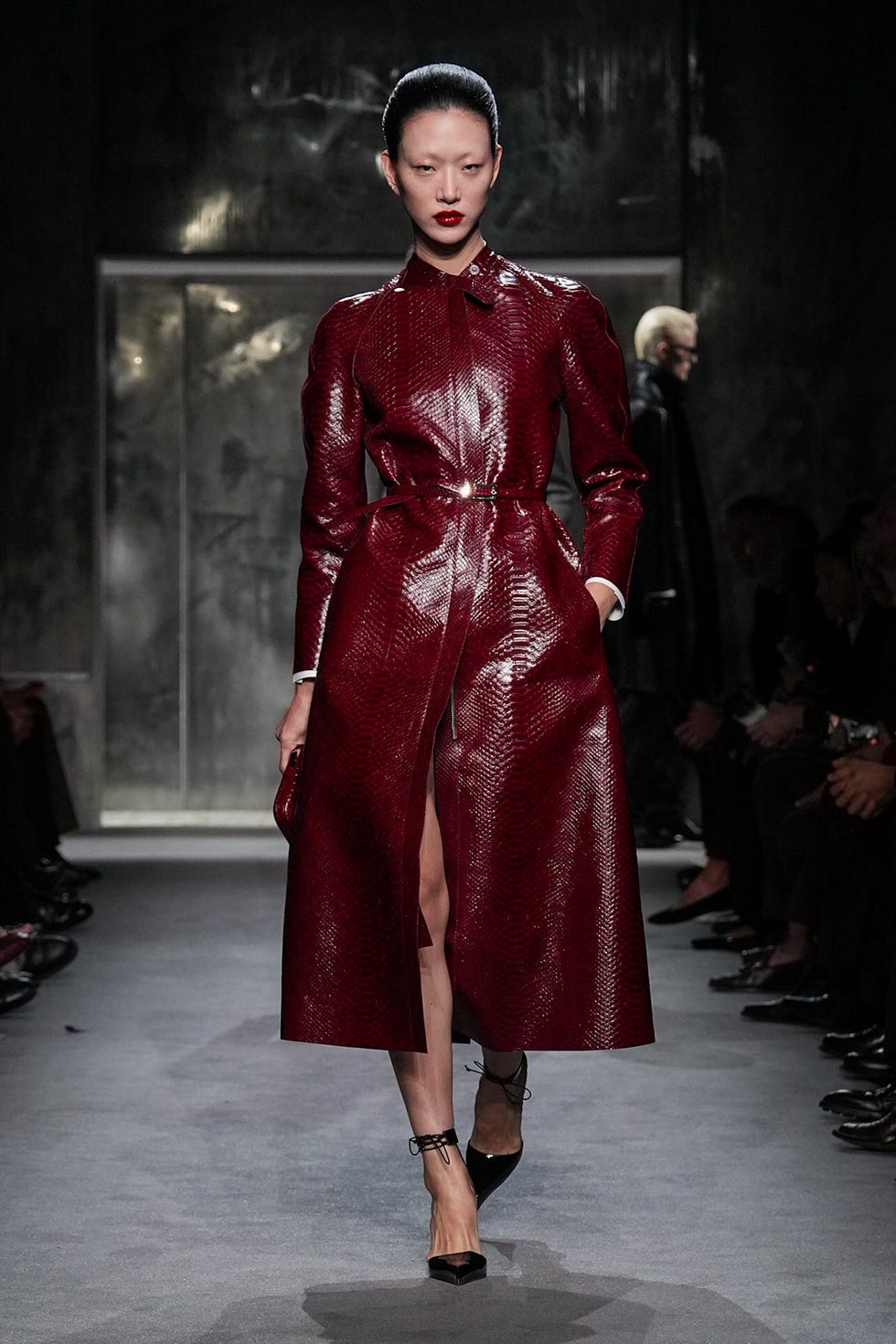 fashion model showcasing a striking red coat in a runway setting