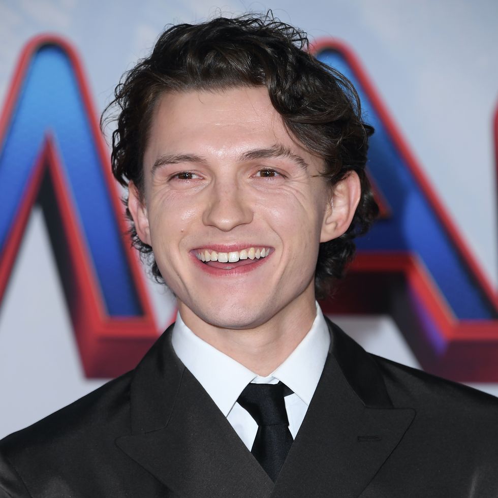 tom holland smiling in a black suit