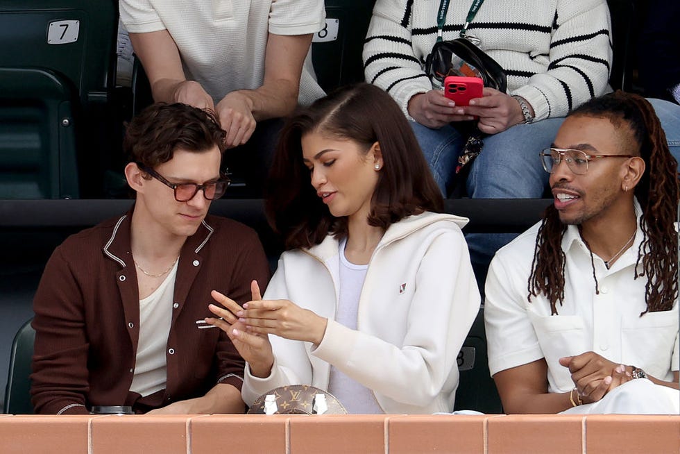 zendaya and tom holland watching bnp paribas open 2024 final day zendaya is wearing a white cardigan and tom is wearing a brown shirt over a white vest top