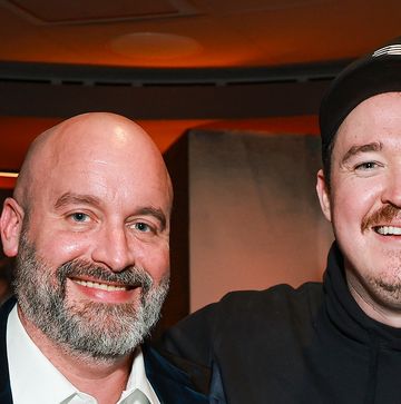 a man in a black hat and sweatshirt smiles at the camera