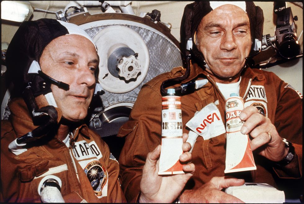 Tom Stafford and Deke Slayton holding tubes of vodka given to them by Russian cosmonauts during historic rendezvous and linkup of Apollo and Soyuz spacecraft.