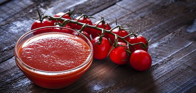 Tomato sauce with fresh tomatoes on dark wooden table