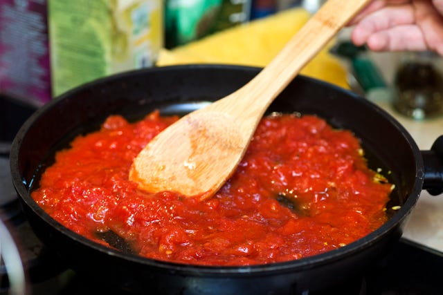 tomato sauce in frying pan with wooden spatula