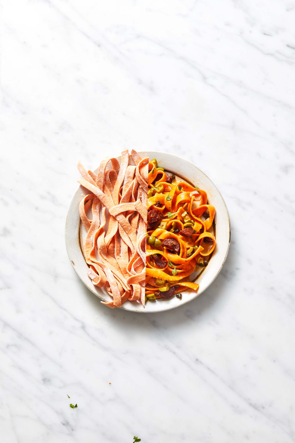 tomato tagliatelle with chorizo and olives in a white plate