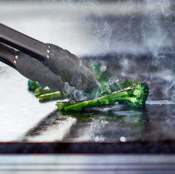 tongues turning fresh broccoli on hot plate