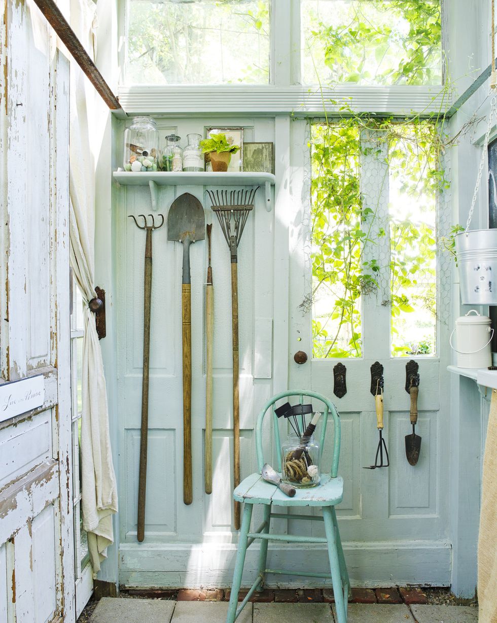 garden tools inside potting shed made of old blue doors