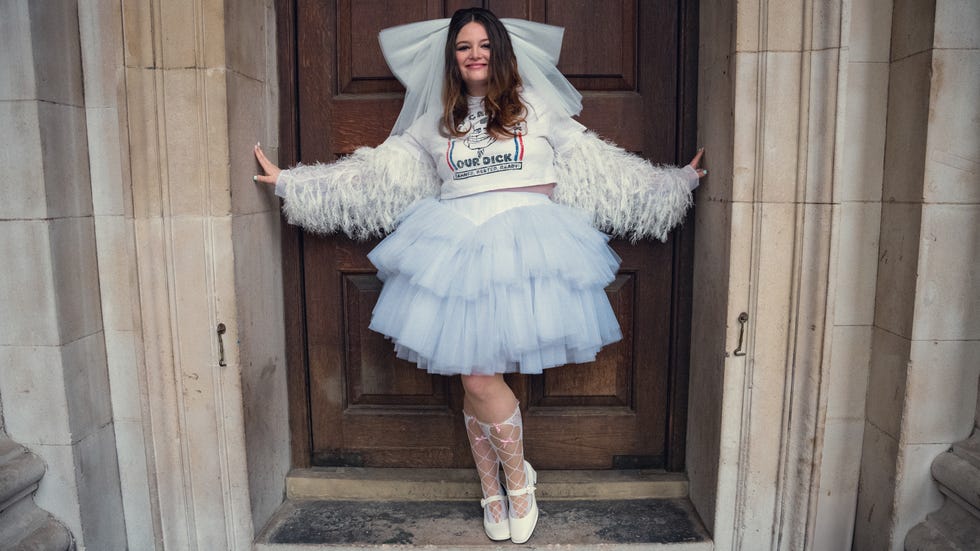 a person wearing a unique outfit standing against a wooden door