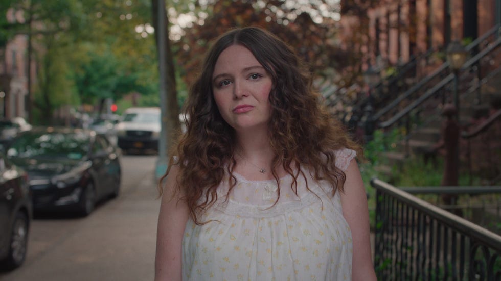 a woman walks down the street in a nightgown