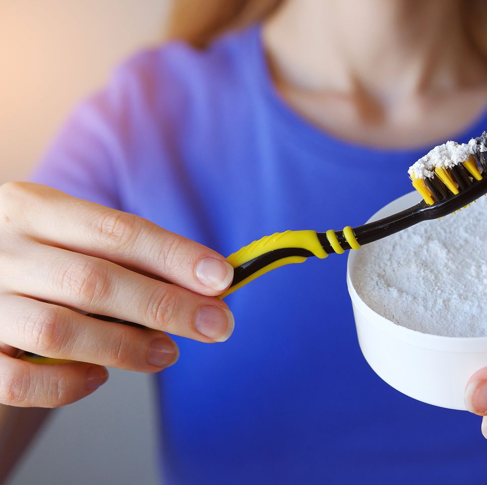 tooth powder for teeth whitening on the toothbrush in the hands of the girl. a young woman holds funds for the care and cleaning of the oral cavity. the concept of health. copy space..