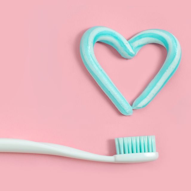 toothbrushes and turquoise color toothpaste in shape of heart on pink background dental and healthcare concept