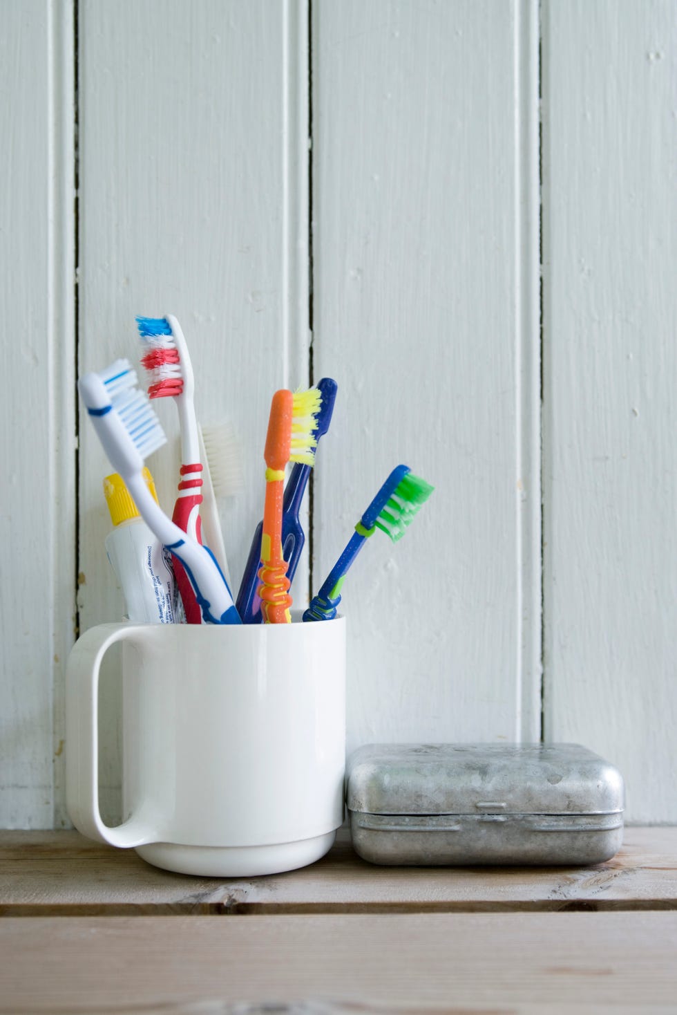 Toothbrushes in mug on shelf