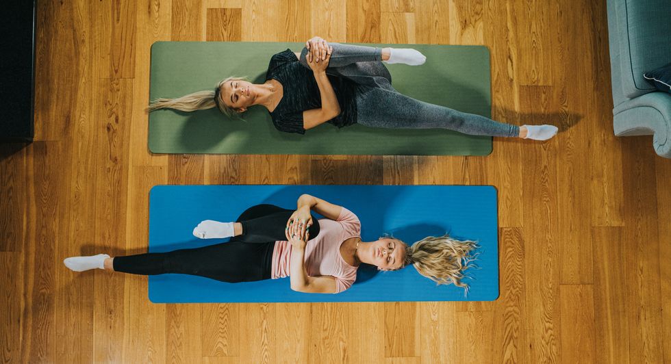 top down image of two woman on yoga mats holding their knee to their chest