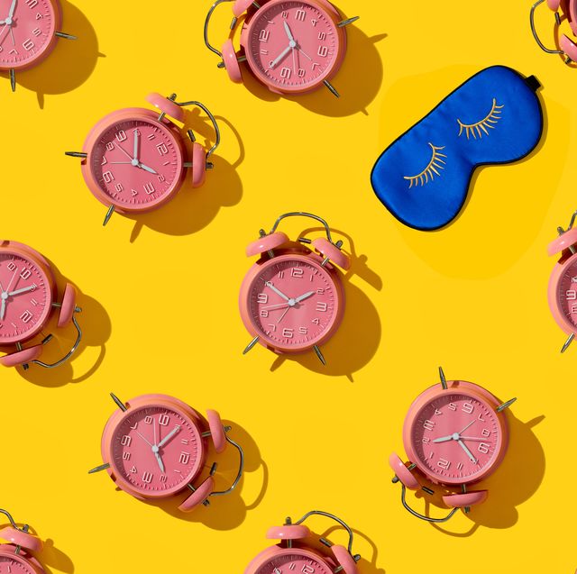 top view of creative pattern made of pink alarm clocks and sleeping mask on a yellow background