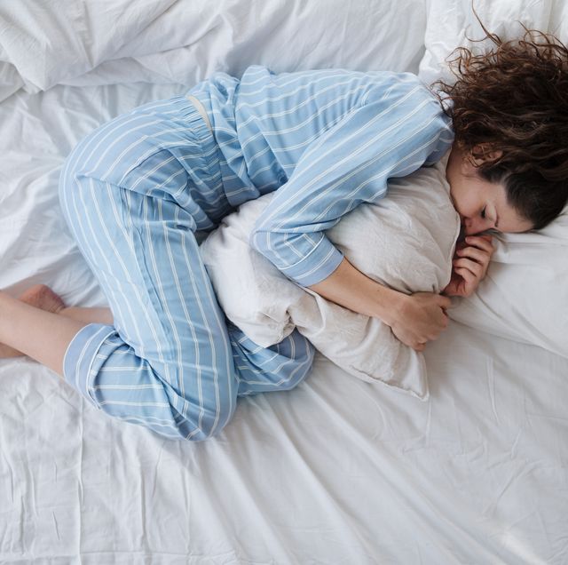 top view of depressed woman in pajamas lying in bed in bedroom