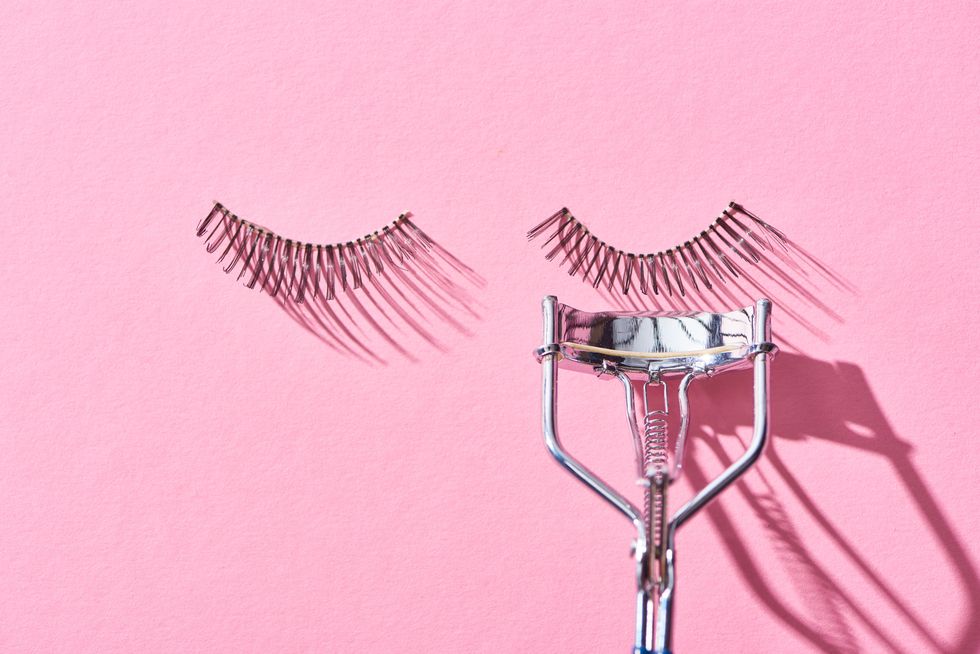 top view of false eyelashes and eyelash curler on pink background