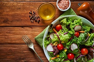 top view of fresh and healthy salad in a bowl on wooden table