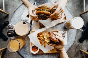 top view of friends having a good time eating burgers with french fries and drinks in a cafe