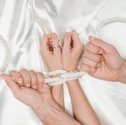 top view of male hands tightly bounding female hands with rope