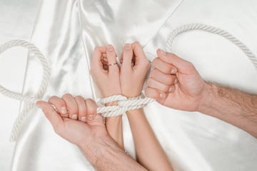 top view of male hands tightly bounding female hands with rope